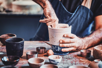 Fototapeta na wymiar Man is putting colourful clay to his new handmade pot.