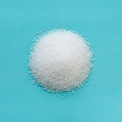 heap of sugar in the shape of a circle on a blue background, macro