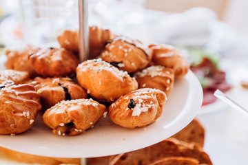 Pies with sesame seeds on a multi-tiered plate. Buffet table at the party.