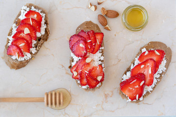 Toast or bruschetta  with cheese , strawberry, almond and honey  on marble board. Top view        