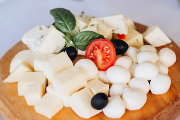 cheese plate with a bunch of grapes, honey and nuts. Gouda, parmesan, mozzarella, gorgonzola on a wooden board.