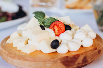 cheese plate with a bunch of grapes, honey and nuts. Gouda, parmesan, mozzarella, gorgonzola on a wooden board.