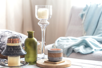 Beautiful burning candles with bottles on white table