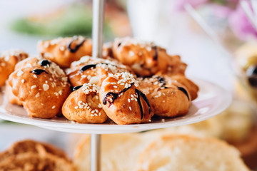 Pies with sesame seeds on a multi-tiered plate. Buffet table at the party.