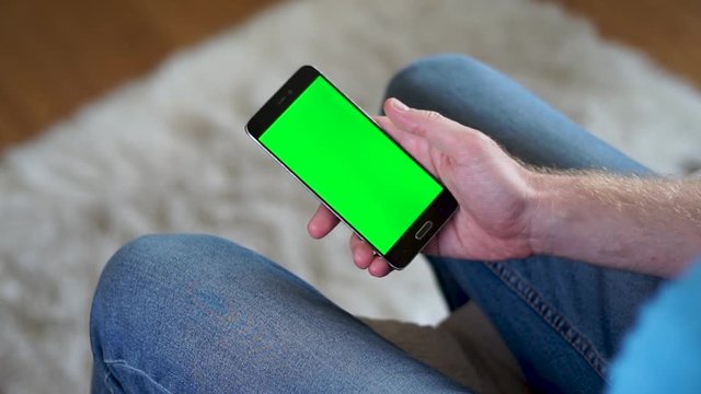Male hand swiping up on a phone with a green screen