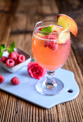 Delicious raspberry peach mimosa drink on a wooden background