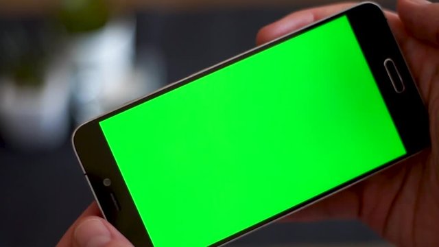 Male hands phone with a green screen horizontally and watching a video