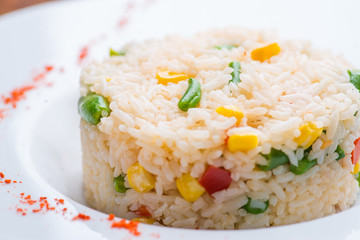 boiled rice with vegetables in a white plate on a wooden table