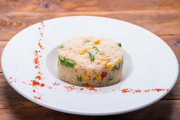 boiled rice with vegetables in a white plate on a wooden table