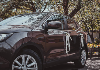 Festive car decorated with white roses and bows on the door handles.