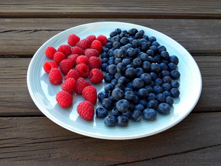 blueberries and raspberries in a plate on a wooden table
