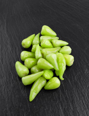 Marinated chili pepper on a slate board. Close-up of several pickled chili peppers on a stone surface.