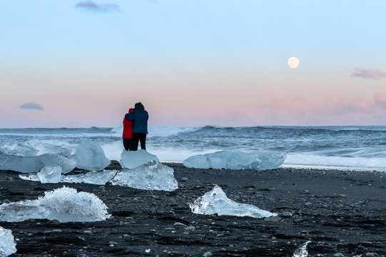 Couple on diamond beach, Jokulsarlon, Iceland.