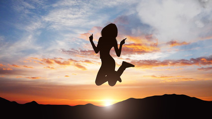 Fototapeta na wymiar Silhouette of jumping woman against sunset background