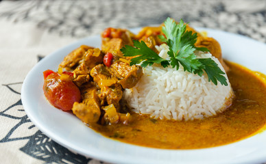 Curry chicken bright juicy with white rice on plate over the tablecloth background. side view.