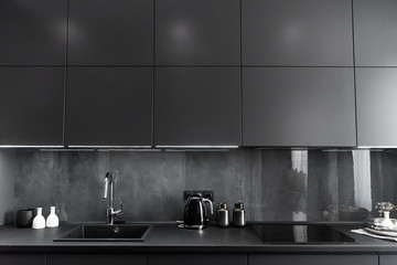 Fototapeta na wymiar stylish kitchen interior in grey and black colors, black worktop and grey backsplash