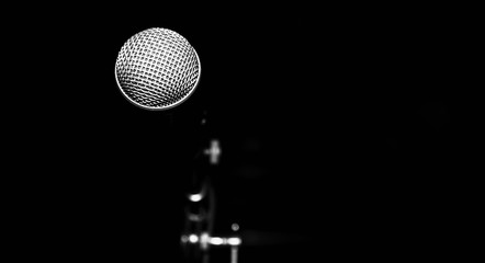 Public performance on stage microphone against black background of concert hall. Black and white photography