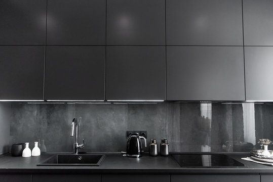 stylish kitchen interior in grey and black colors, black worktop and grey backsplash