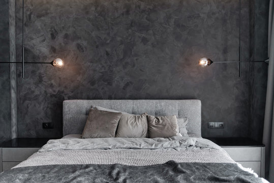 Master bedroom for a lonely stylish man, a bachelor. Modern room with trendy gray interiors, large king-size and lamps.