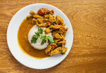 Curry chicken bright juicy with white rice on plate over wooden background. Top view, flat lay.