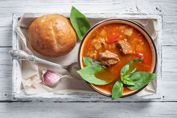 Bowl of goulash in box on white rustic table. Traditional hungarian meal.  - obrazy, fototapety, plakaty