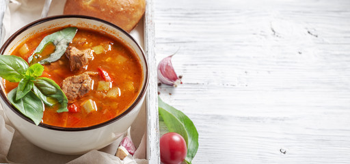Bowl of goulash in box on white rustic table with copy space