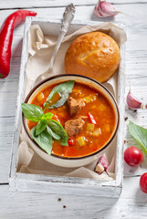 Bowl of goulash in box on white rustic table. Traditional hungarian meal. 