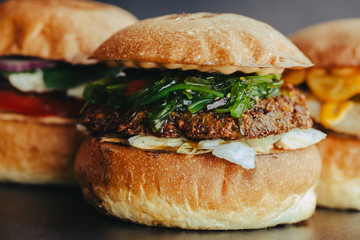 Burger flyer. Cheese burger with grilled meat, cheese, salad and onion rings. Close-up of delicious fresh home made burger with salad and cheese on bark blue background