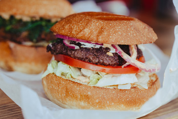 Two Classic Luxurious Authorized Burger with Cheese, with Lettuce, Onions, Tomatoes and Bun on a Wooden Background