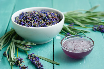 a pile of fresh lavender flowers and syrup on blue wooden table background