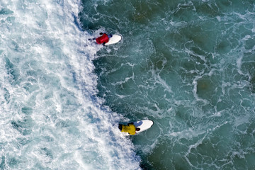 Aerial shot from surfers trying to catch a wave in the ocean