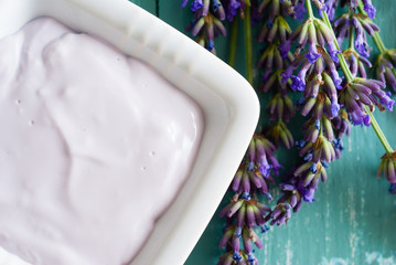 lavender soaps and cosmetic cream, flowers on blue wooden table