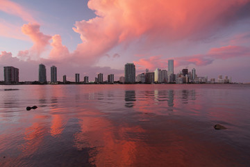 A very colorful cloudscape over the City of Miami skyline reflected on the calm waters of Biscayne...