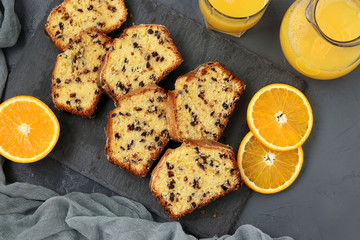 Cupcake with oranges and chocolate, located on a slate stand against a dark background, top view