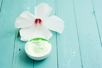 cosmetic cream and white mallow flower on blue wood table