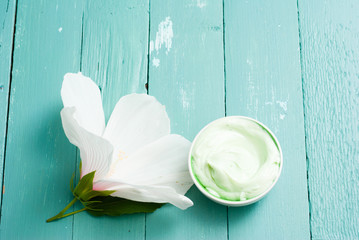 cosmetic cream and white mallow flower on blue wood table