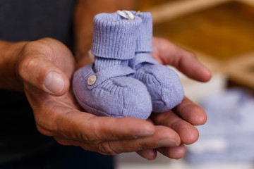 Blue baby shoes on hands of man