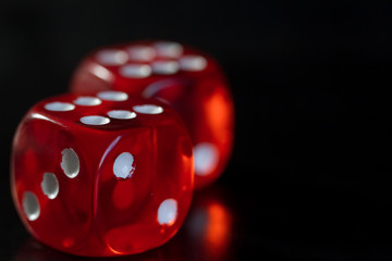 Closeup of a two red dice with a winning number on the top face on a black mirror surface