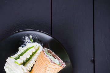 Ice cream cone on black background, summer concept. Dessert with jam on black plate. Waffle cone with ice cream in minimalism style. Copy space
