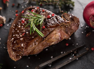 Grilled beef steak on black stone table, close-up