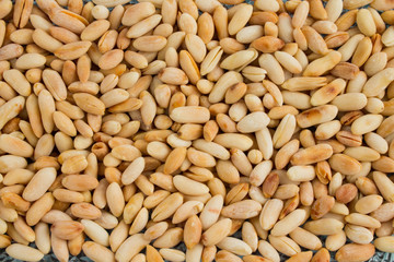 background of small roasted peanuts scattered on a ceramic plate.
