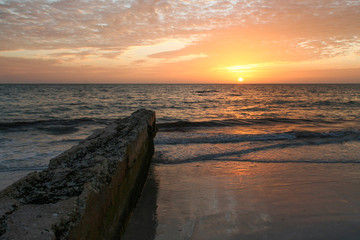 Sunset on a beach with an old pier in the foreground.  Siesta Key, FL, USA.