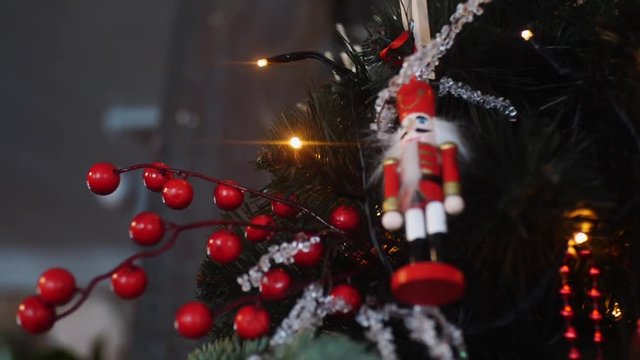 Close-up view of traditional Christmas holiday nutcrackers figurine hanging on a Christmas Tree near the lights and other decorations. Frame. Christmas mood