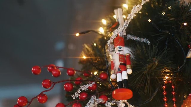 Close-up view of traditional Christmas holiday nutcrackers figurine hanging on a Christmas Tree near the lights and other decorations. Frame. Christmas mood