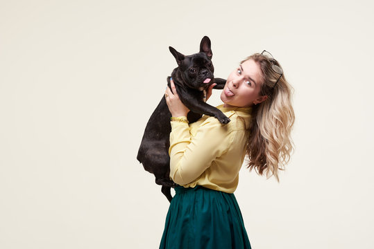 Veterinary concept. Happy hipster woman playing with french bulldog on white background. Owner with funny dog resting, hugging and having fun. space for text