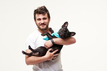 Hipster Bearded guy holding and hugging a nice French Bulldog dog in his arms with love and playing...