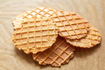 Thin round waffles on a wooden background, close-up