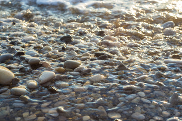 pebble stones on the sea beach, the rolling waves of the sea with foam