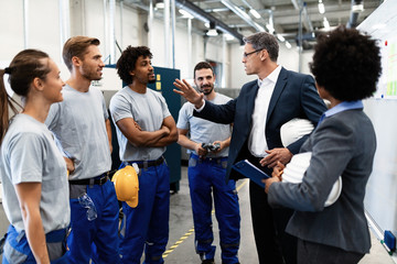 Company manager having a meeting with group of workers in industrial plant.