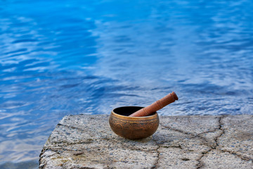 Singing bowl with engraving pattern and wooden stick on natural background with copy space for text.